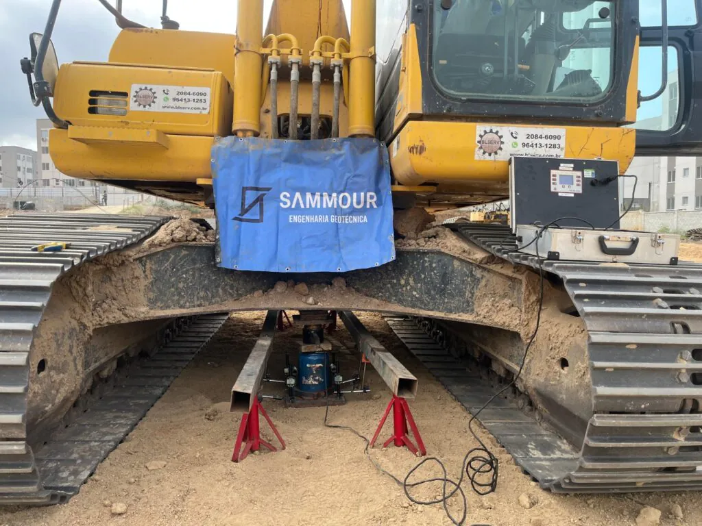 Sistema de reação com escavadeira e contrapeso da Sammour Engenharia montado sobre a placa para prova de carga direta no solo
