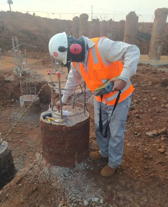 Engenheiro Sammour segurando placa de atenção em canteiro com escavação e contenção