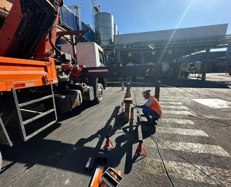 Técnico realizando ensaio de placa com caminhão caçamba e equipamentos de medição