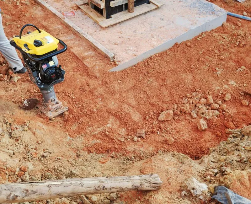 Fôrma de bloco de fundação concretado com armadura de aço e compactador de solos em canteiro de obras