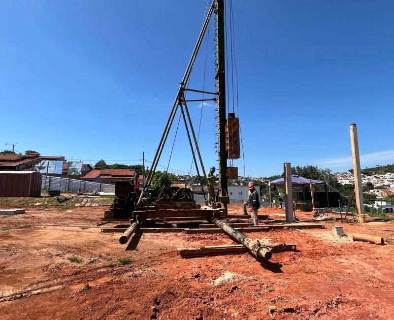 Bate-estacas em canteiro urbano com técnico operando cravação de estacas para fundações